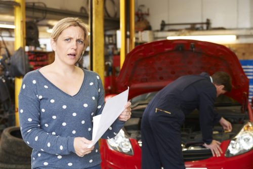 Blonde woman with shocked face while her car is fixed