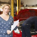 Blonde woman with shocked face while her car is fixed