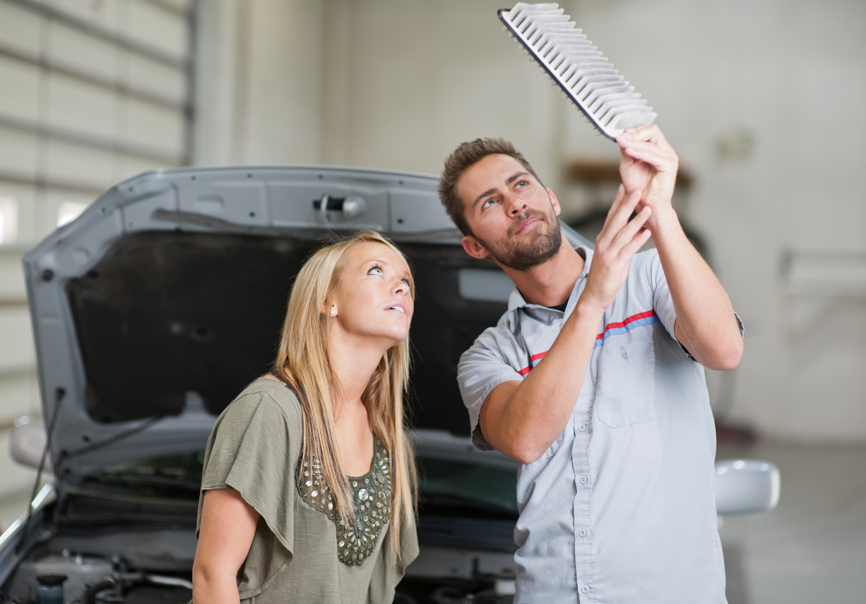 Mechanic shows air filter to female customer during maintenance