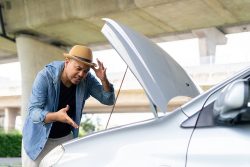 Frustrated,Young,Asian,Man,Looking,At,Broken,Down,Car,Engine